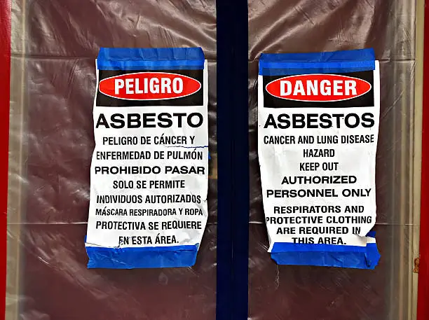 Bilingual asbestos hazard warning signs at containment entrance